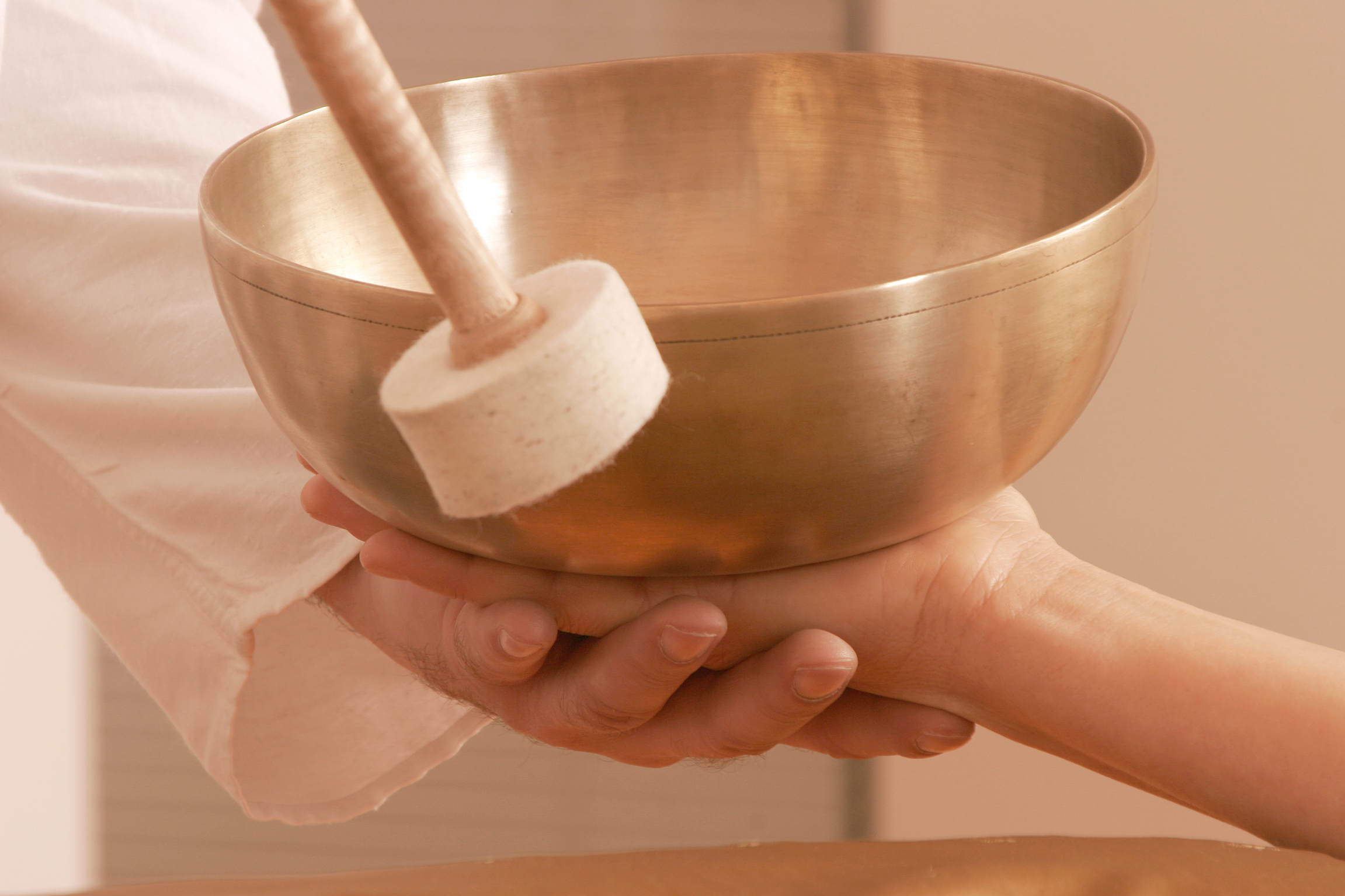 Bol chantant tibétain tenu dans les mains, prêt à être mis en vibration avec sa mailloche